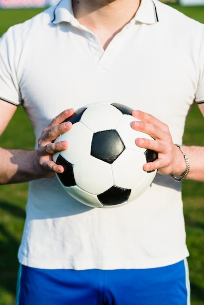 Deportista de la cosecha que sostiene el nuevo balón de fútbol