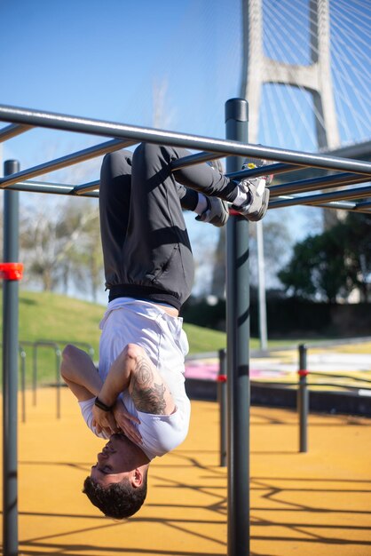 Deportista enfocado trabajando en un día soleado. Hombre ropa deportiva en campo de deportes al aire libre, tirando hacia arriba en las barras. Deporte, salud, concepto de ejercicio.