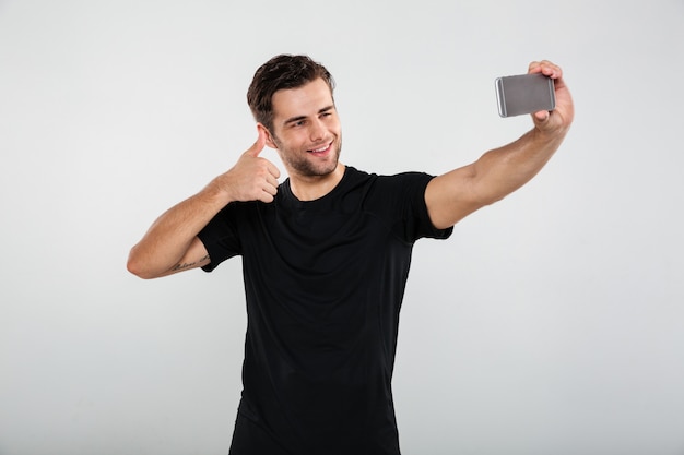 Deportista feliz hacer selfie por teléfono móvil.