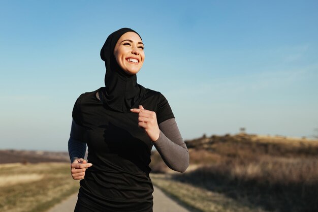 Deportista feliz sintiéndose motivada mientras corre en la naturaleza Copiar espacio