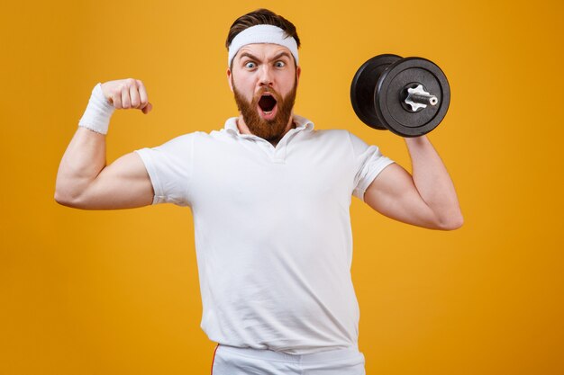 Deportista gritando sosteniendo pesas y mostrando bíceps