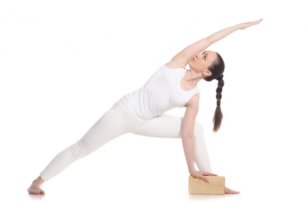 Deportista haciendo ejercicios de yoga con un bloque de madera