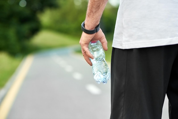 Deportista manteniendo la botella de agua de pie en la pista de carreras