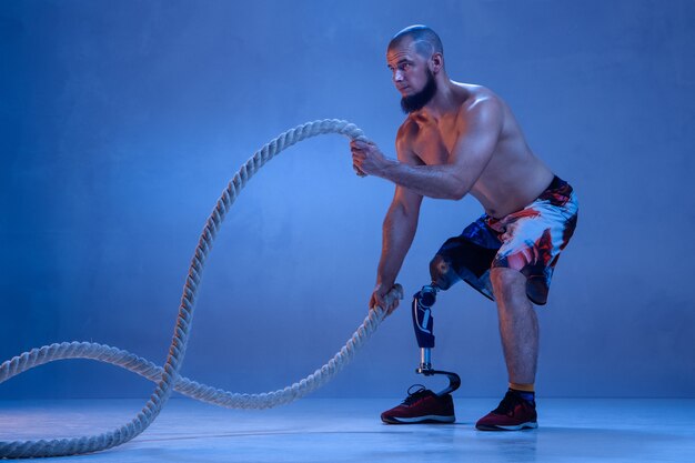 Deportista masculino profesional con entrenamiento de prótesis de pierna con cuerdas en neón