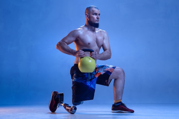 Deportista masculino profesional con entrenamiento de prótesis de pierna con pesas rusas