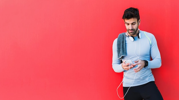 Deportista que usa el teléfono inteligente sobre fondo rojo