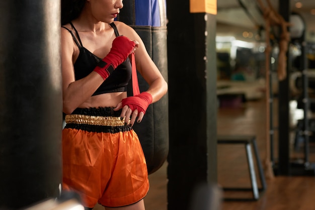 Deportista recortada preparándose para el ejercicio de boxeo en un gimnasio