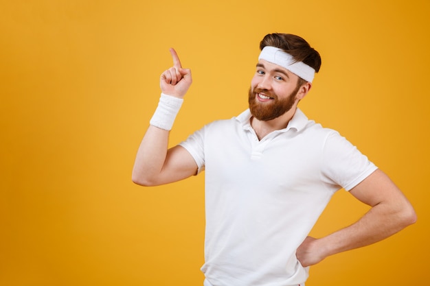 Deportista sonriente sosteniendo el brazo en la cadera y apuntando hacia arriba