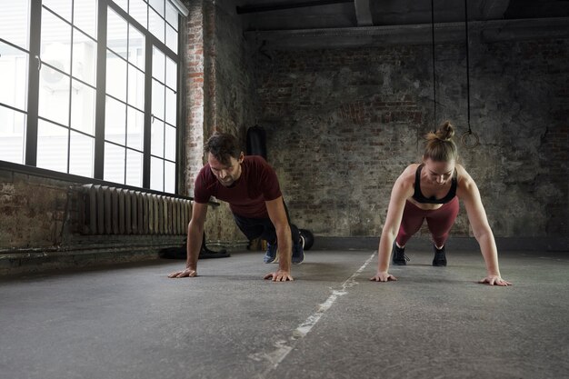 Deportistas de tiro completo haciendo burpees dentro