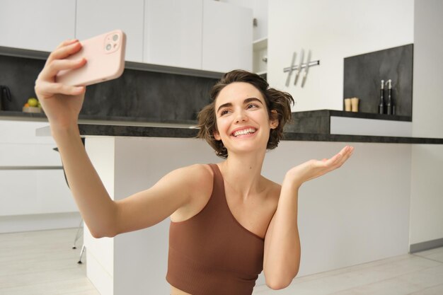 Deportiva joven atleta femenina toma selfie en entrenamiento de teléfono inteligente desde casa y hace fotos rec