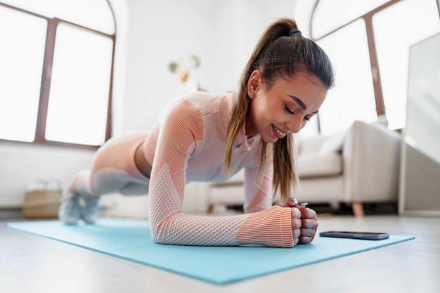 Deportiva joven haciendo ejercicio de tabla en el interior de casa