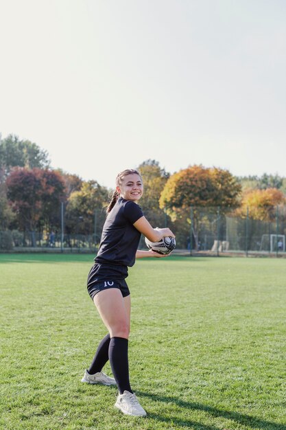 Deportiva jovencita sosteniendo una pelota de rugby