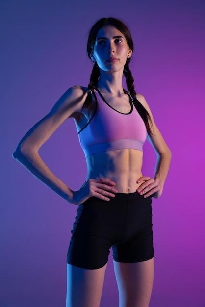 Deportiva mujer atleta profesional en uniforme posando aislado fondo de estudio púrpura en luz de neón