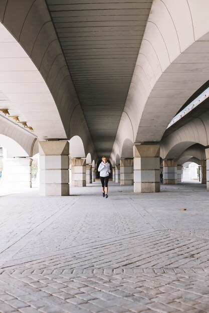 Deportiva mujer corriendo cerca de columnas