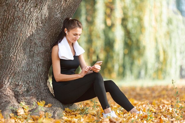 Deportiva mujer descansando cerca de un árbol