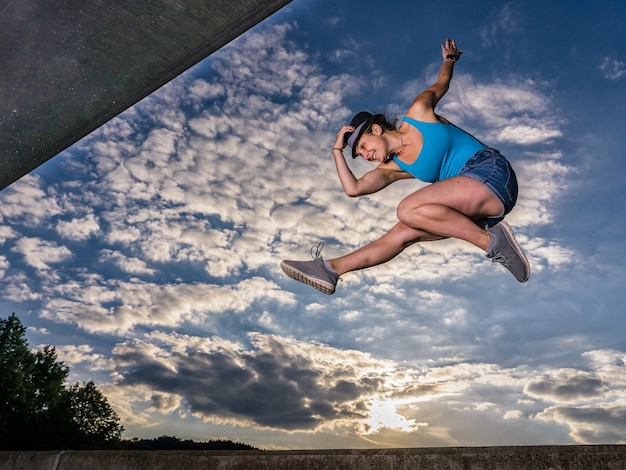 Deportiva mujer europea saltando en el aire sobre fondo de cielo nublado