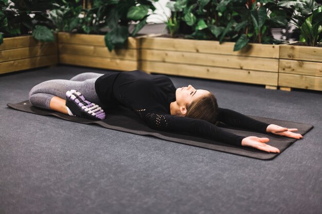 Deportiva mujer joven haciendo ejercicio en la estera de yoga