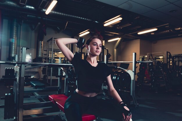 Deportiva mujer joven haciendo ejercicio con pesas en el gimnasio