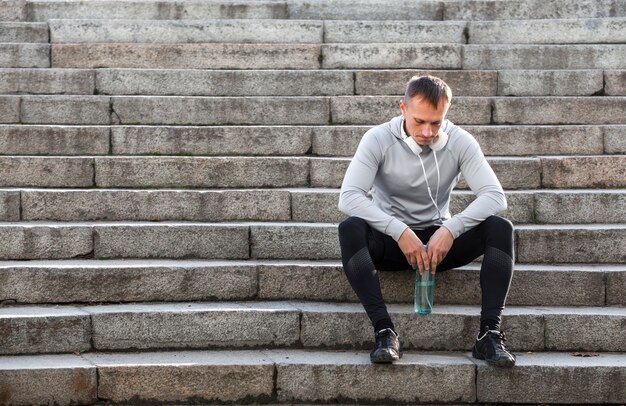 Deportivo hombre descansando en las escaleras