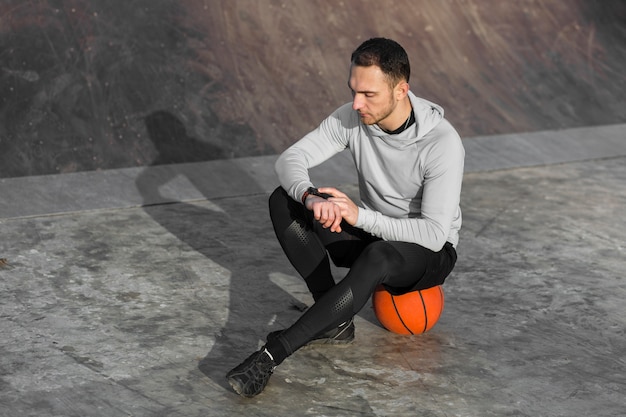 Deportivo hombre descansando sobre una pelota de baloncesto