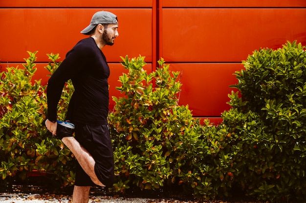 Deportivo hombre estirando su pierna al aire libre