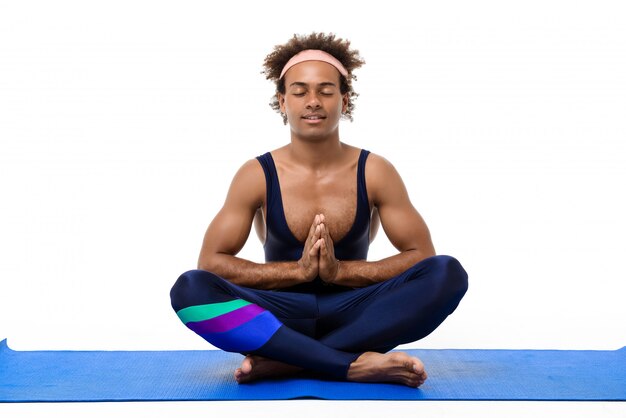 Deportivo hombre meditando, sentado en la estera de yoga