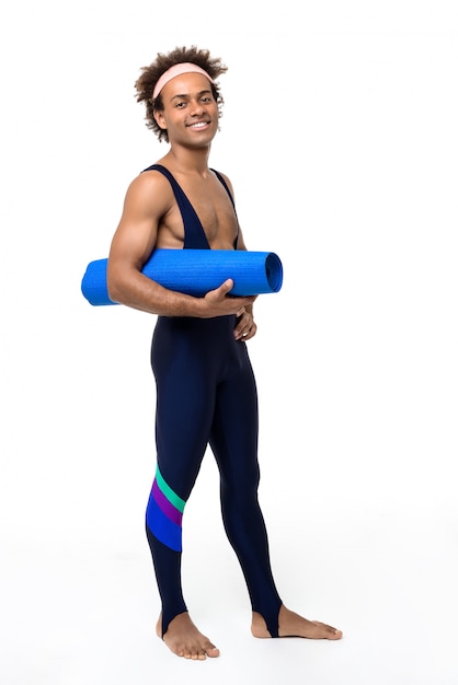 Deportivo hombre sonriendo, sosteniendo estera de yoga