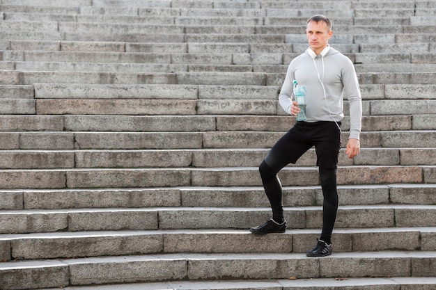 Foto gratuita deportivo hombre sosteniendo una botella de agua en las escaleras