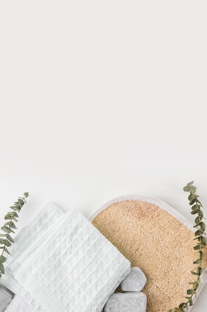 Depurador de cuerpo de esponja circular; Servilleta de algodón y piedras de spa con ramitas aisladas sobre fondo blanco