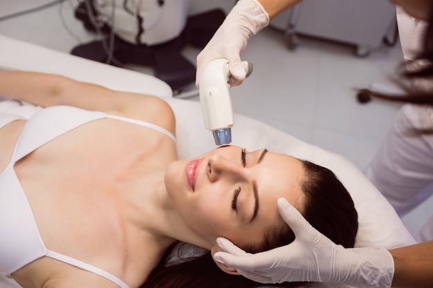 Dermatólogo dando masaje facial a través de levantamiento sonoro