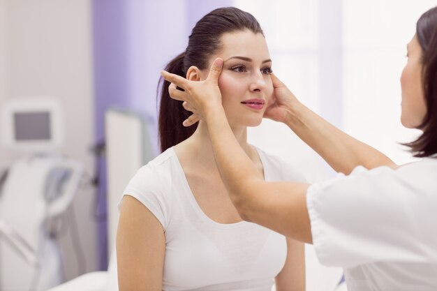 Dermatólogo examinando la piel del paciente femenino