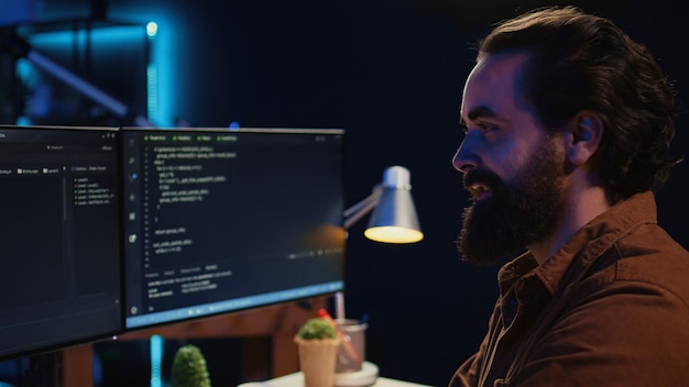 Desarrollador independiente sonriente en la oficina de casa haciendo programación en la computadora