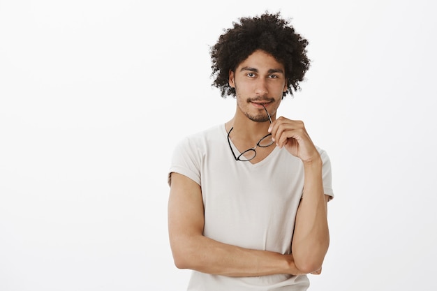 Desarrollador joven masculino guapo pensativo haciendo plan, pensando en la pared blanca