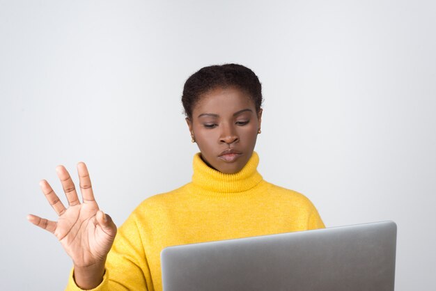 Desarrollador reflexivo que sostiene la computadora portátil y toca la pantalla virtual