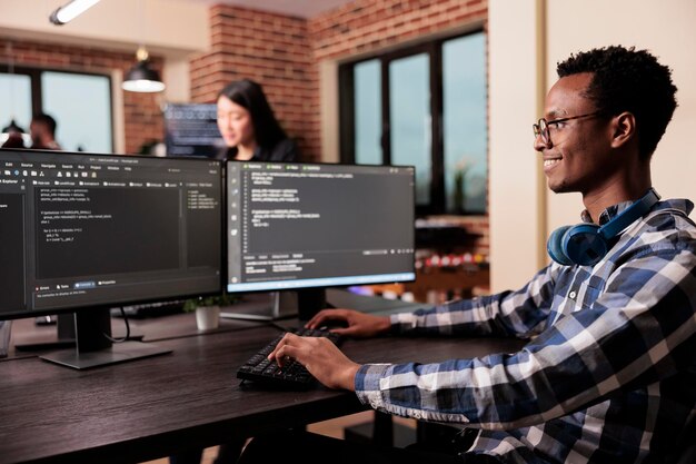 Desarrollador de software que trabaja en una nueva interfaz de usuario con un sistema en línea para crear un algoritmo en la oficina de la agencia de IT. Ingeniero de sistemas programando un algoritmo de código html en la computadora, escribiendo datos sever