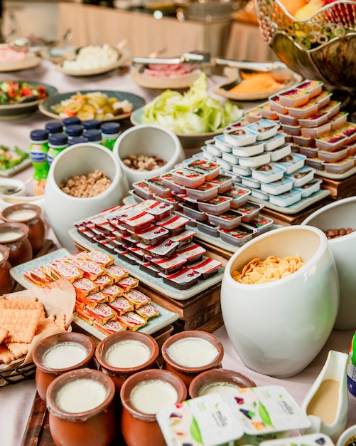 Desayuno buffet con mermeladas de mantequilla, yogures y cereales.