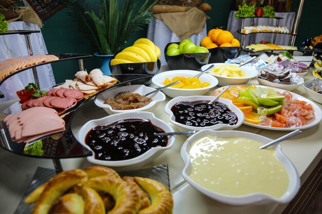 Desayuno buffet salchichas jamón frutas verduras mermeladas vista lateral