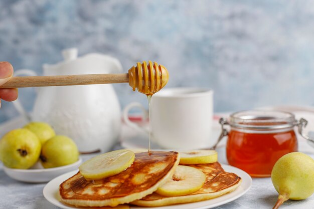 Desayuno casero: tortitas de estilo americano servidas con peras y miel con una taza de té en concreto. Vista superior y copia