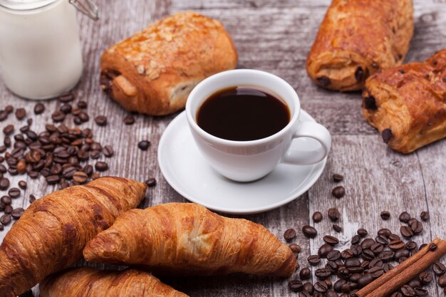 Desayuno con coissants recién hechos con café y leche en la mesa de madera rústica. Croissant dorado.