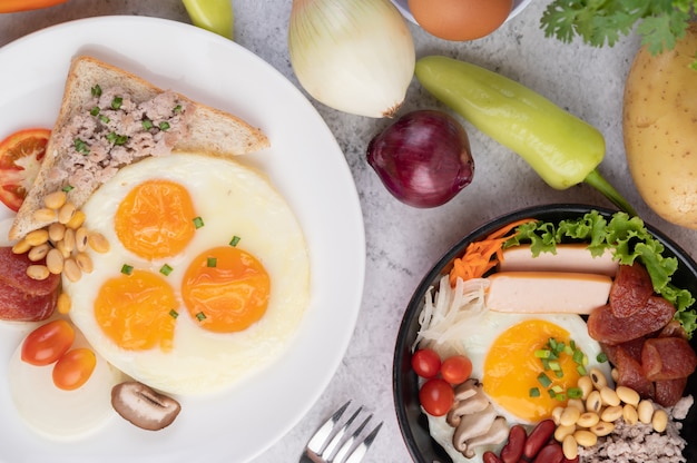 El desayuno consiste en huevos fritos, salchichas, carne de cerdo picada, pan, frijoles rojos y soja en un plato blanco.