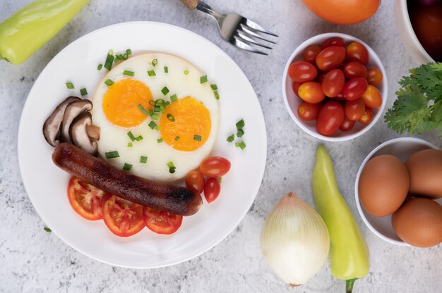 El desayuno consiste en pan, huevos fritos, tomates, salchichas chinas y champiñones.