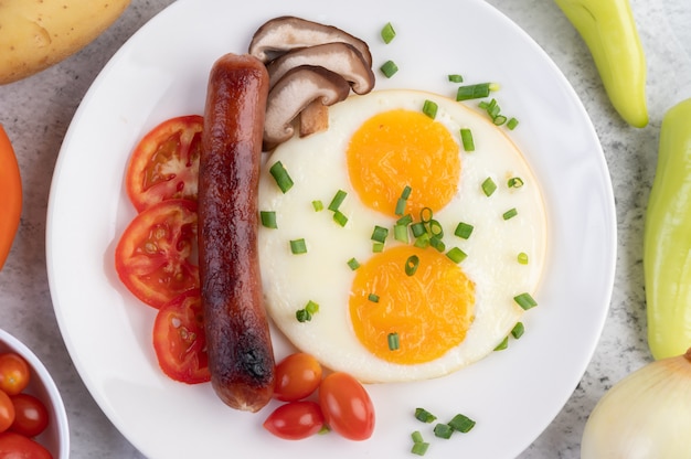 Foto gratuita el desayuno consiste en pan, huevos fritos, tomates, salchichas chinas y champiñones.