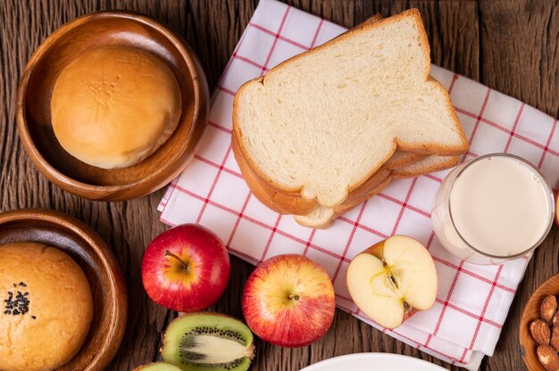 El desayuno consiste en pan, manzanas, uvas y kiwi en una mesa de madera