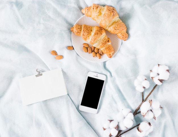 Foto gratuita desayuno con croissant y un móvil