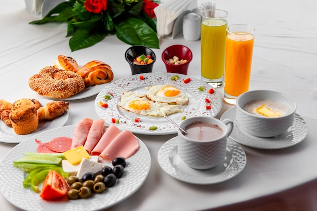 Desayuno delicioso de la opinión de alto ángulo en la tabla con la ensalada, los huevos fritos y los pasteles en el fondo blanco. horizontal