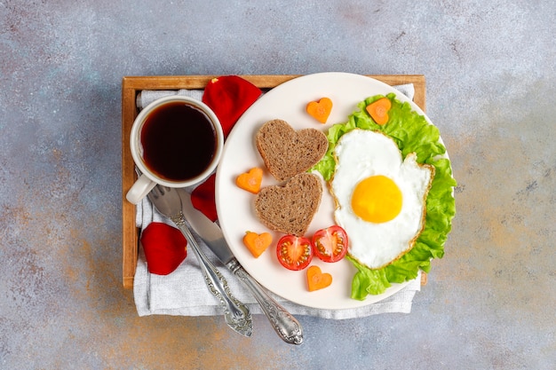 Desayuno el día de San Valentín: huevos fritos y pan en forma de corazón y verduras frescas.