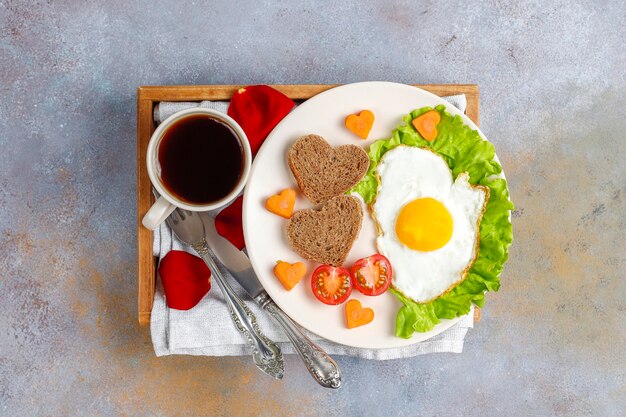 Desayuno el día de San Valentín: huevos fritos y pan en forma de corazón y verduras frescas.