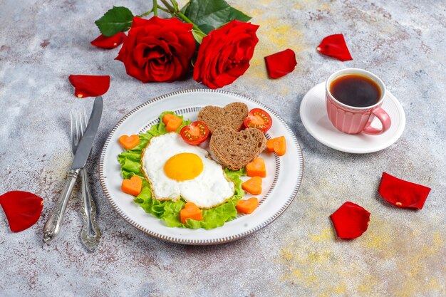 Desayuno el día de San Valentín: huevos fritos y pan en forma de corazón y verduras frescas.