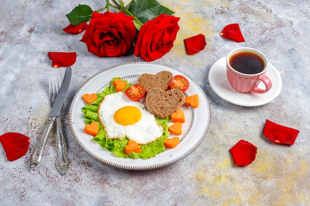 Desayuno el día de San Valentín: huevos fritos y pan en forma de corazón y verduras frescas.