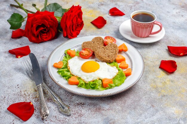 Desayuno el día de San Valentín: huevos fritos y pan en forma de corazón y verduras frescas.